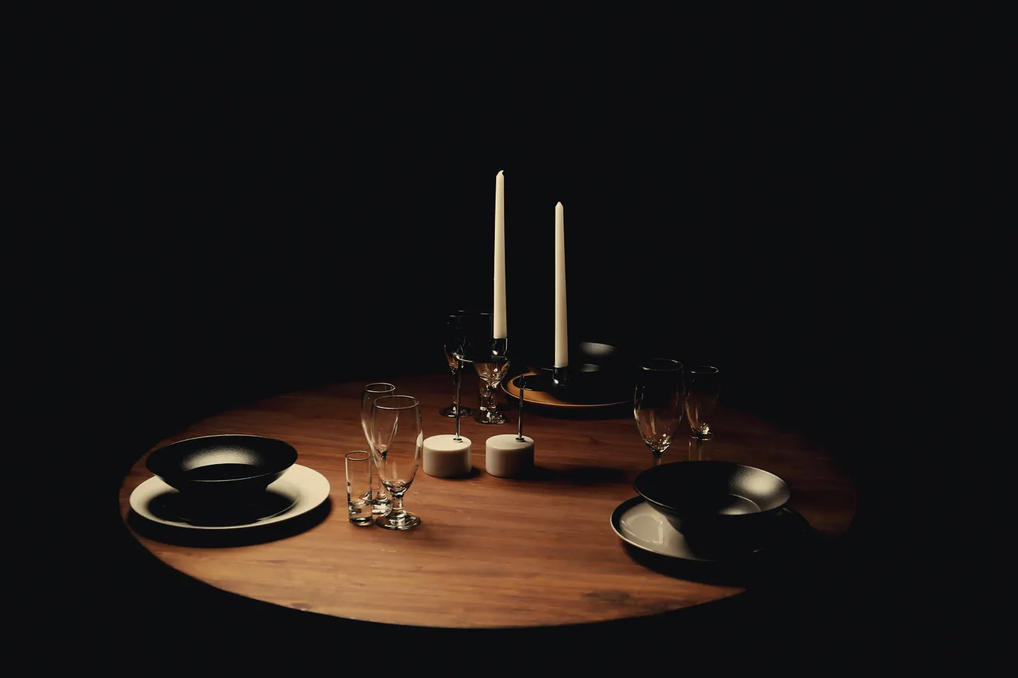 Ett dukat bord vid levande ljus i ett mörkt rum.