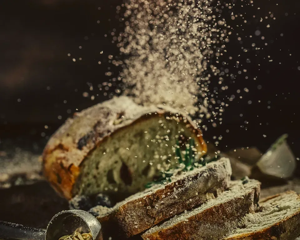 Skivat bröd med örter på ett mörkt bord