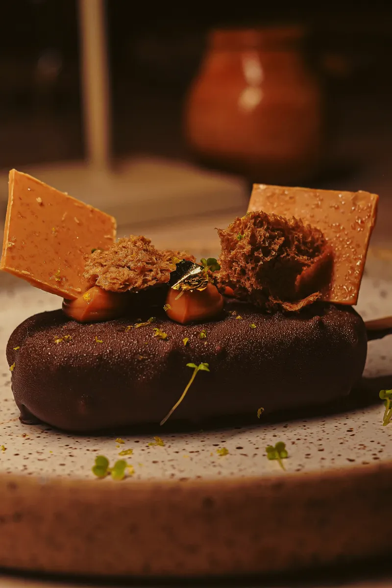 En chokladdessert med spröda detaljer på ett keramikfat