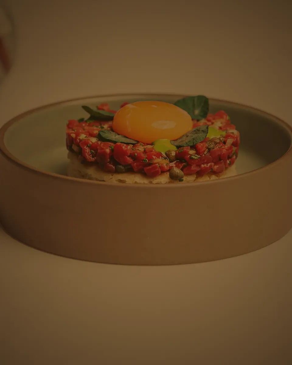Färska råvaror: tartar med äggula och gröna blad i närbild