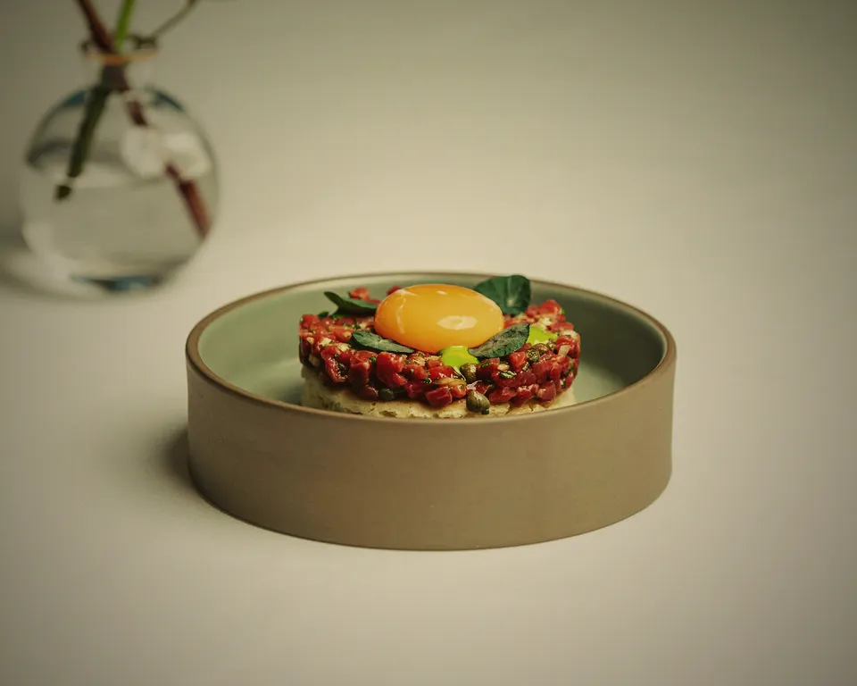 Noggrant upplagd tartar med äggula på ett ljust fat