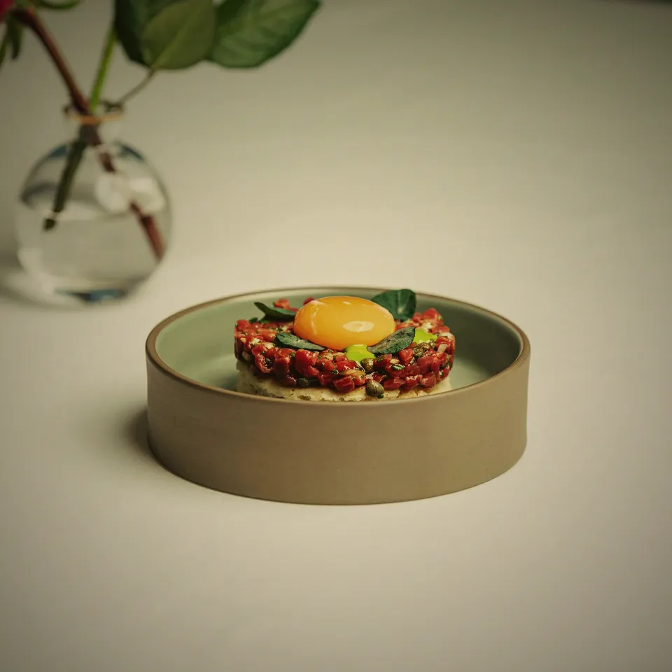 Noggrant upplagd tartar med äggula på ett ljust fat